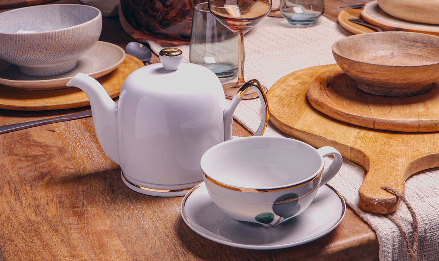 Ceramic teapot and teacup arranged on a dining table.